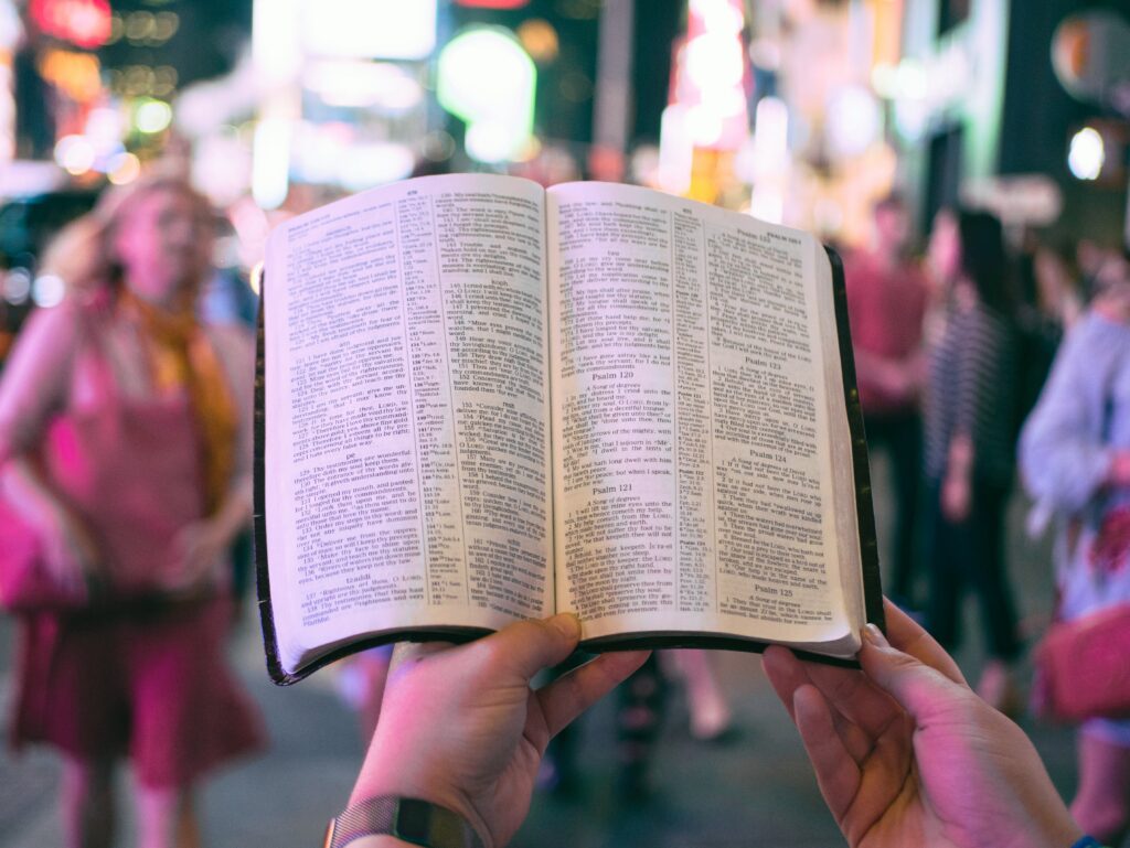 Någon läser en bibel på en folktät gata.